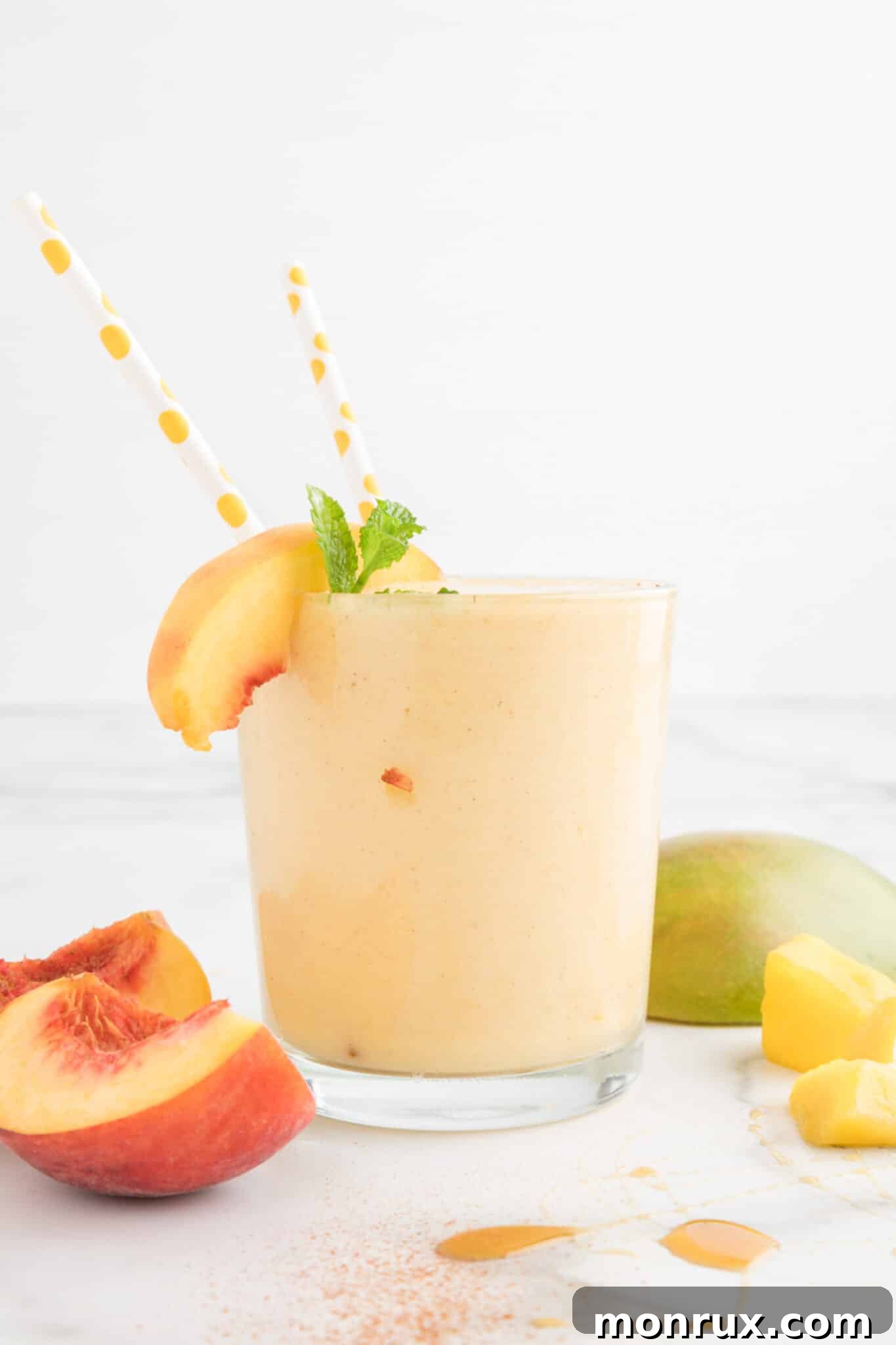Two glasses of mango peach smoothie sit invitingly on a table, ready for a refreshing treat, perhaps with colorful straws.