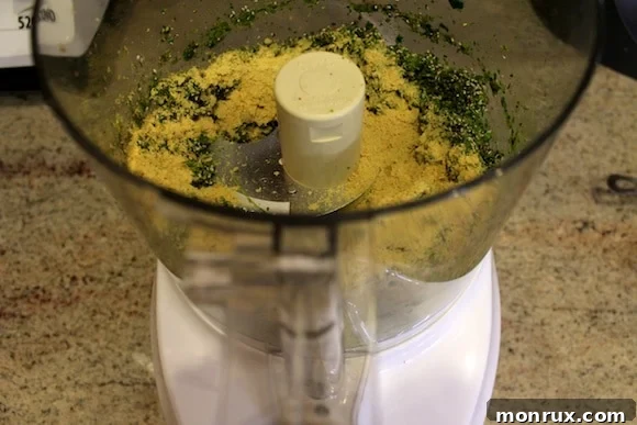 Green juice pulp, nutritional yeast, flax seeds, and chia seeds combined in a food processor bowl, ready for blending.