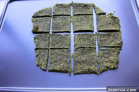 Batch of finished, perfectly crisp green juice pulp crackers laid out on a baking sheet, ready for cooling and serving.