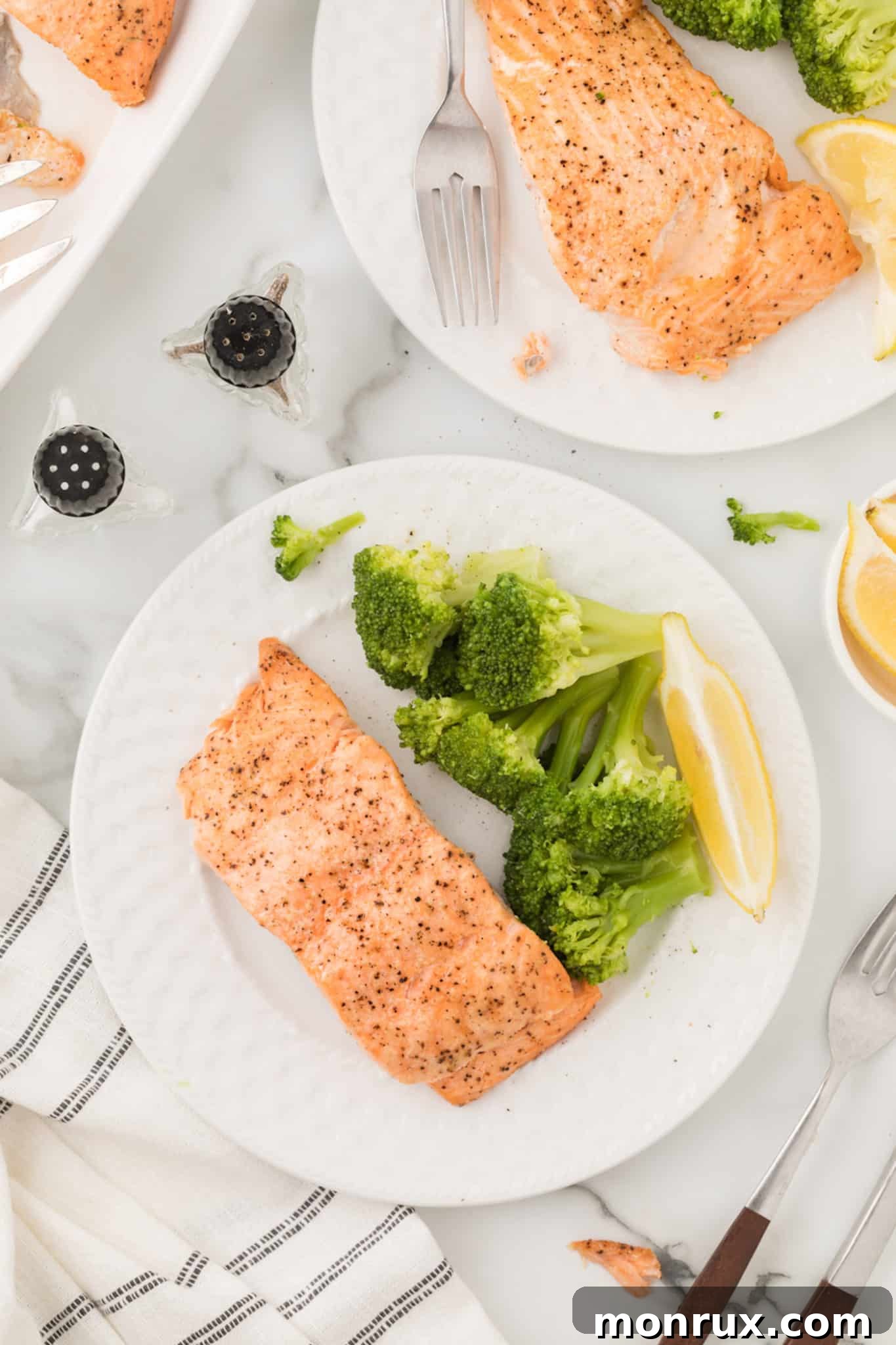 two plates of air fried salmon dinner on a tabletop.