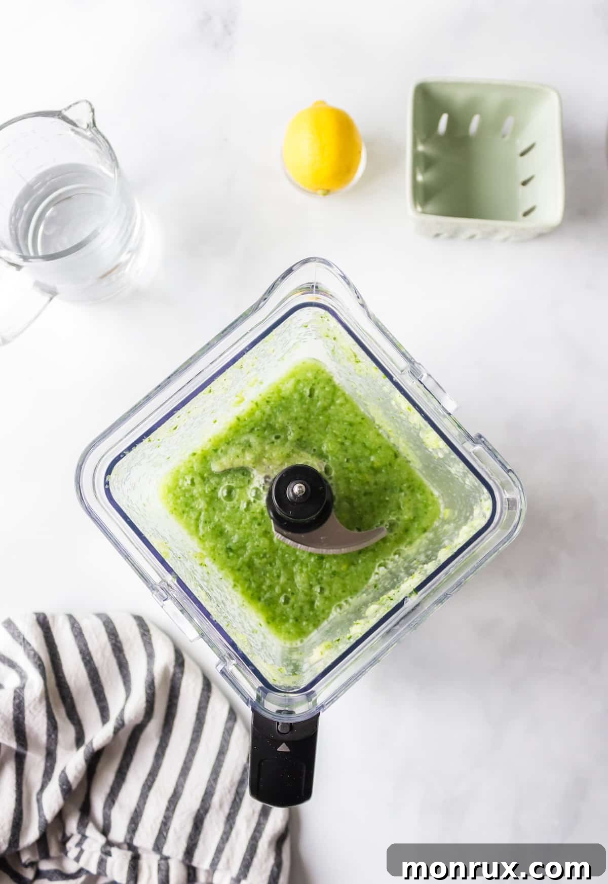 The blended mixture of cucumber, apple, lemon, ginger, and mint forming a smooth green liquid in a blender pitcher.