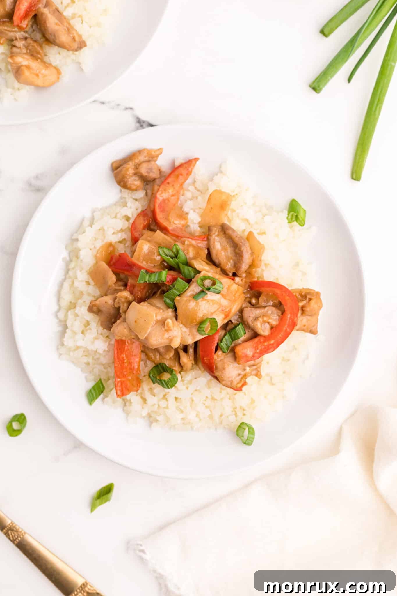 Plated peanut butter chicken with rice and green garnish