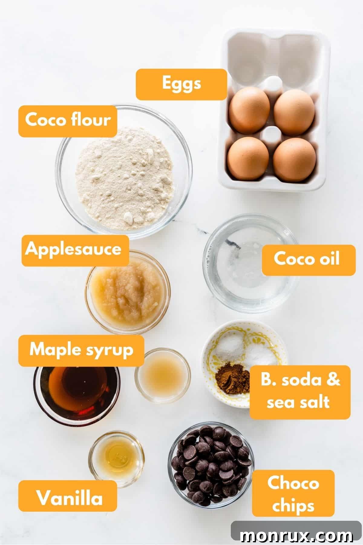 Ingredients laid out for making coconut flour muffins, including coconut flour, eggs, applesauce, coconut oil, and chocolate chips.