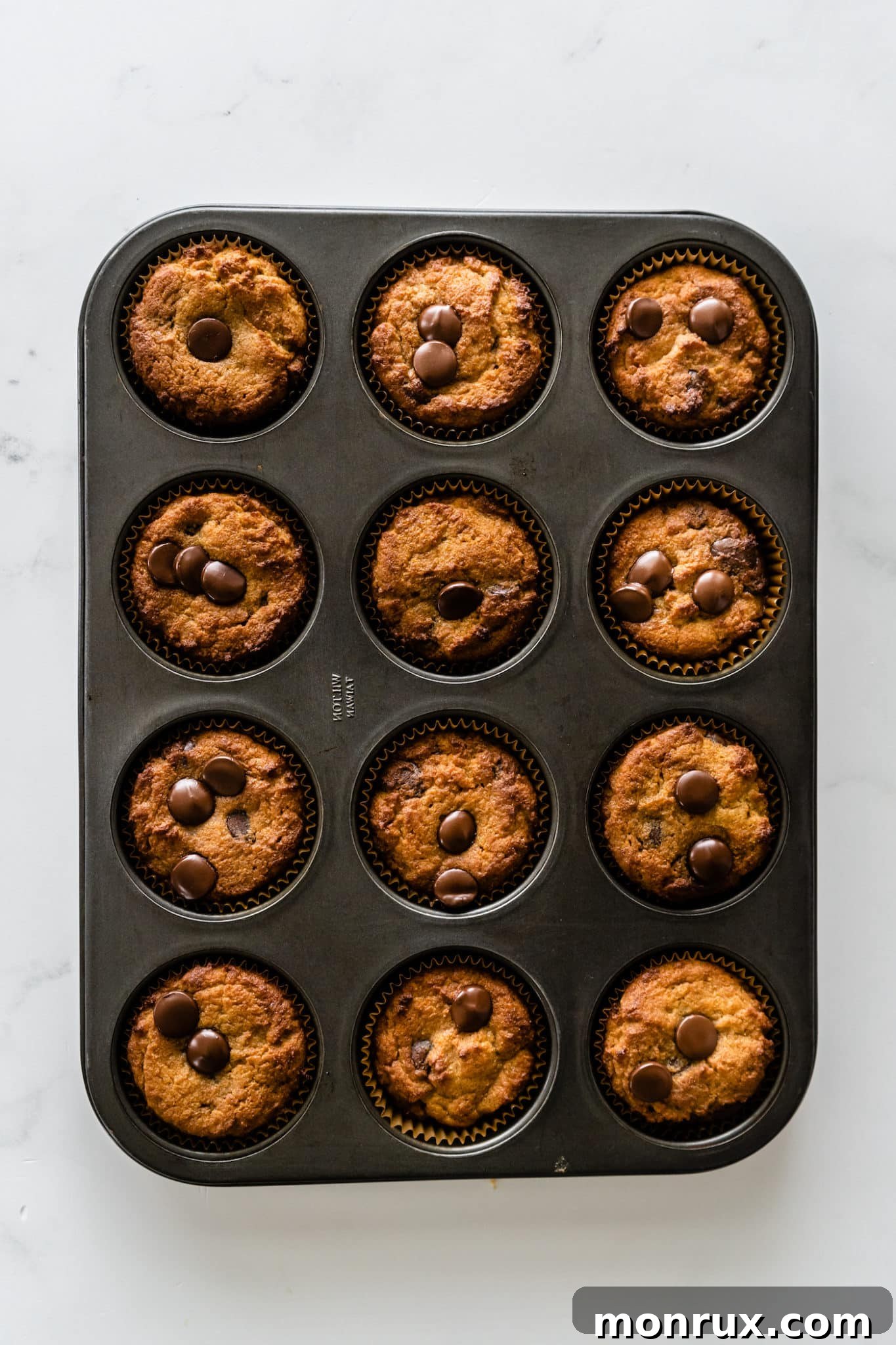 Baked coconut flour muffins in a muffin tin, golden brown and ready to cool.