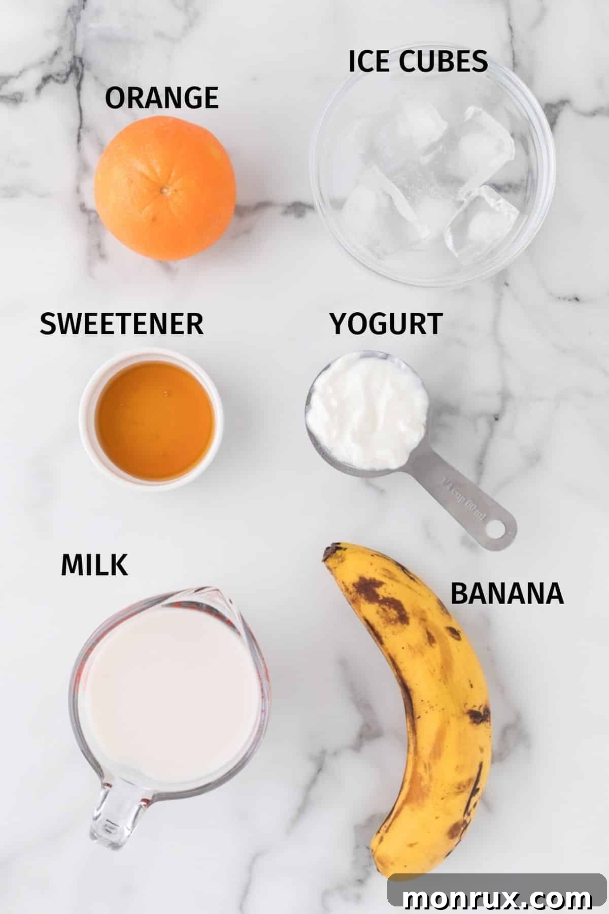 Arrangement of fresh ingredients for an orange banana smoothie, including oranges, bananas, milk, and yogurt, neatly labeled on a table.