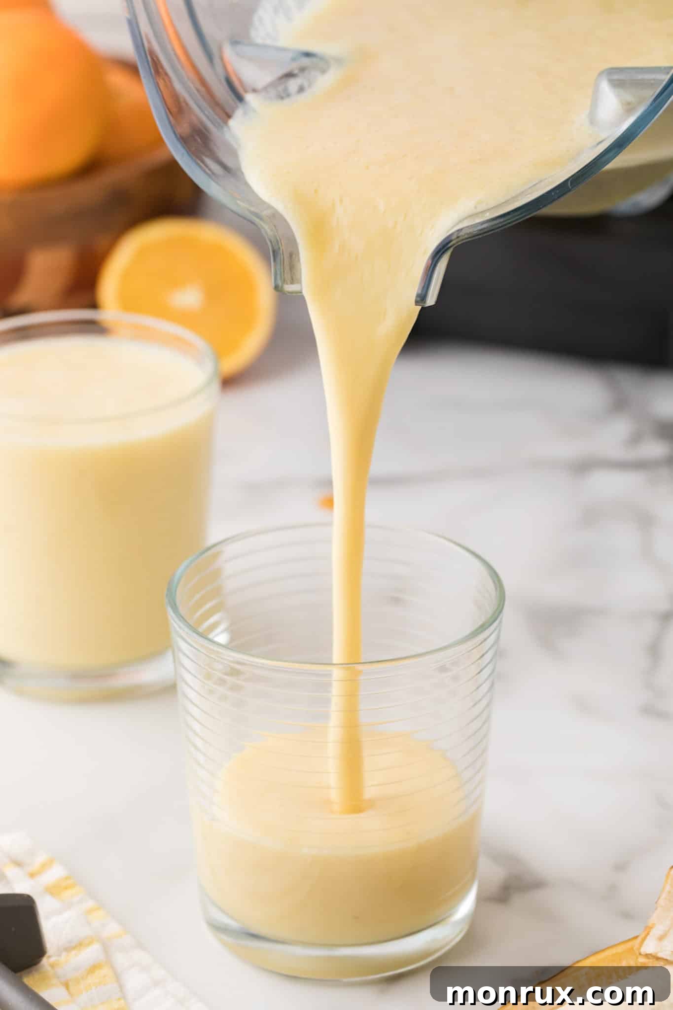 Smoothie being poured into a tall glass, ready to be enjoyed.