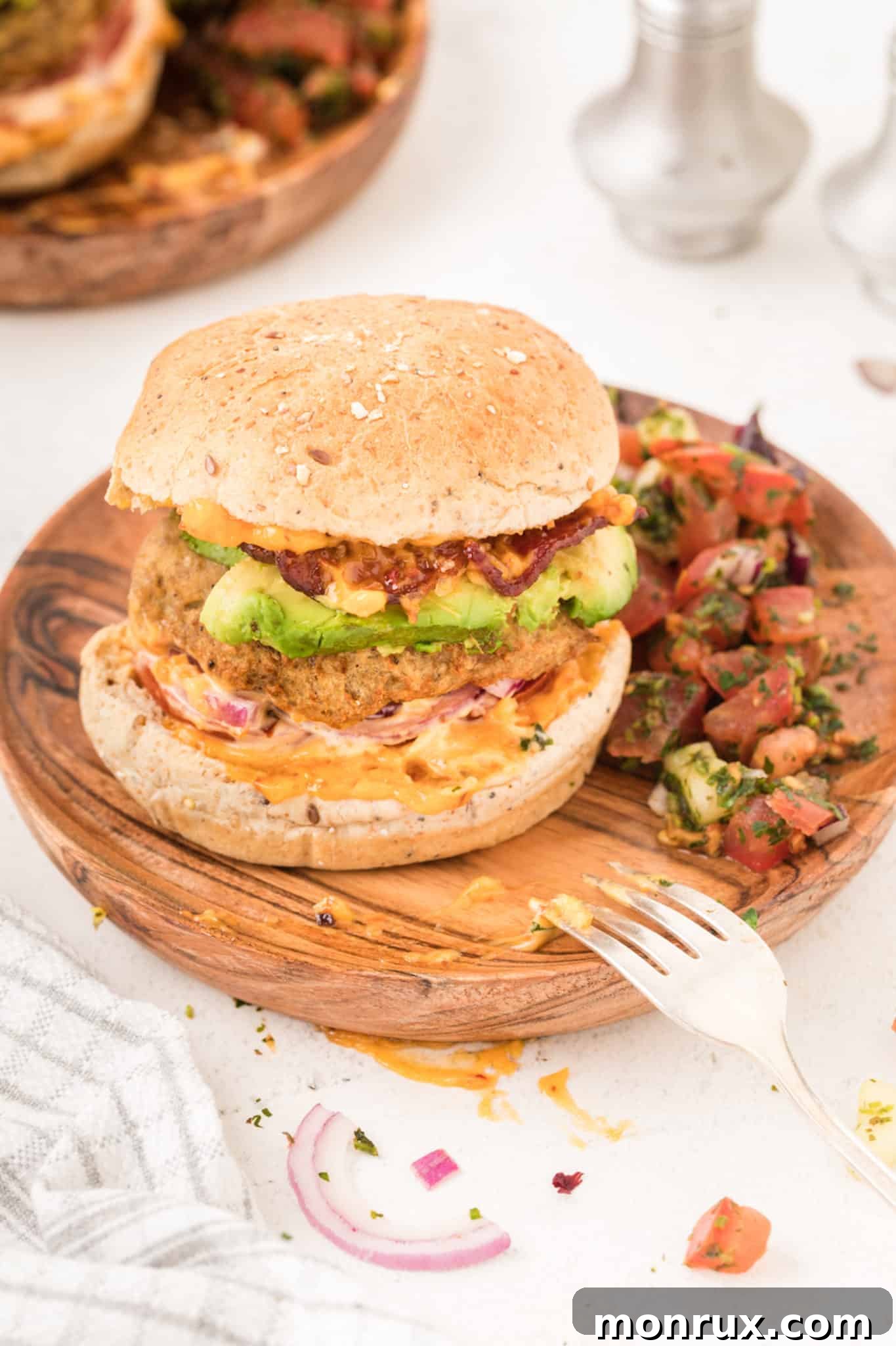 An air fryer turkey burger, perfectly cooked and served on a bun, topped with creamy avocado slices and crispy turkey bacon, ready to be enjoyed.