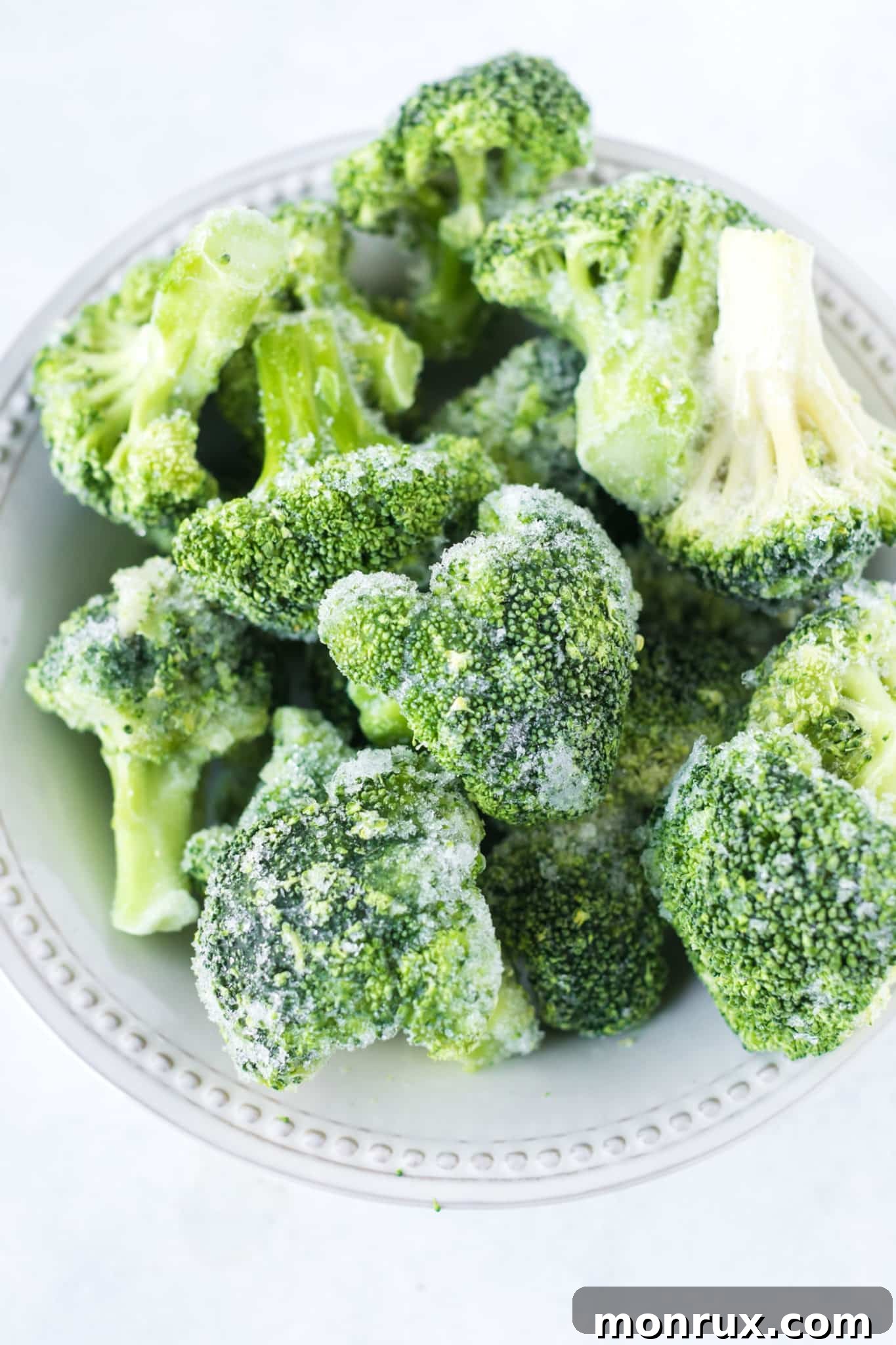 A bowl filled with raw frozen broccoli florets, ready for roasting.