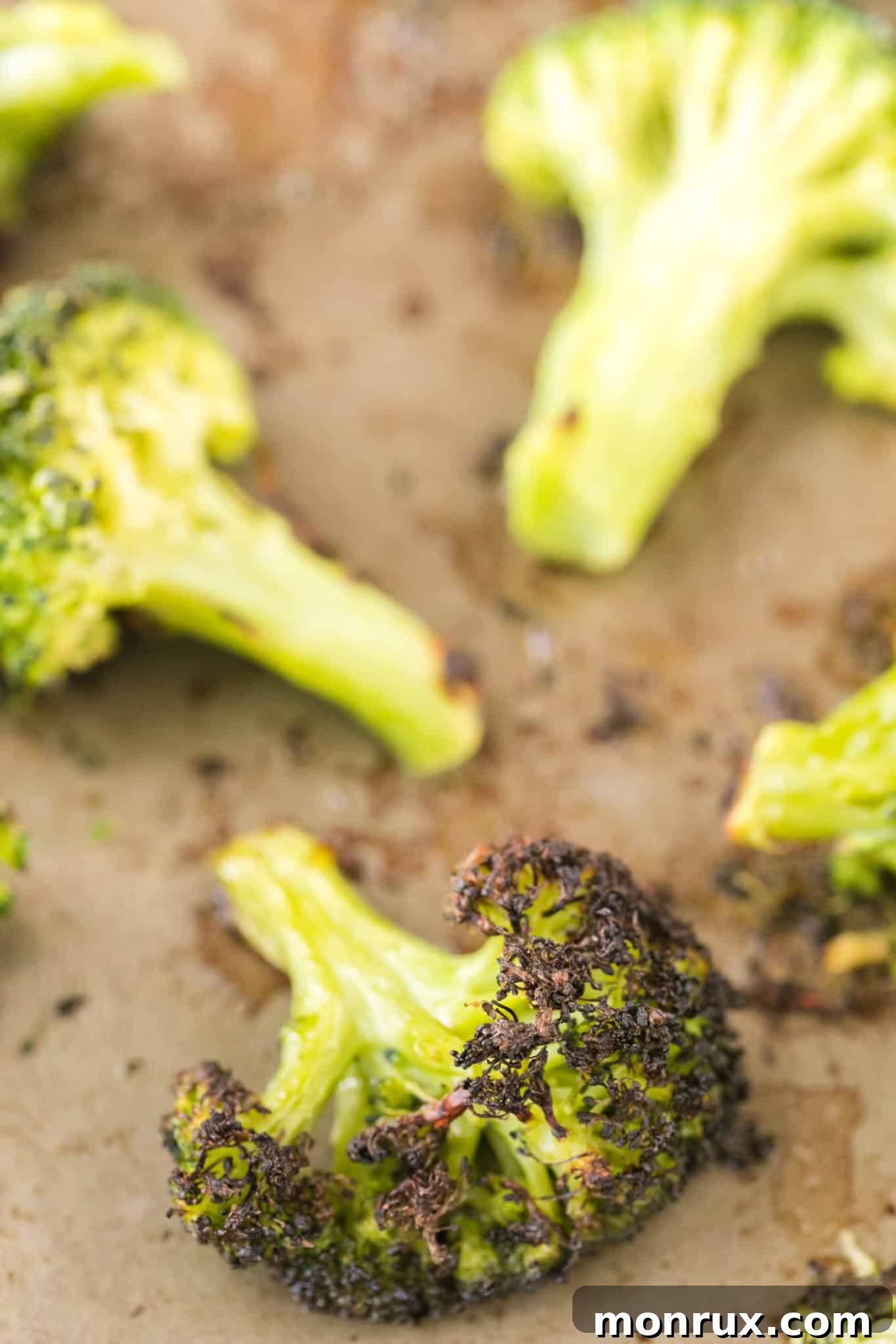 A single perfectly roasted broccoli floret, cooked from frozen, showcasing its crispy texture on a baking sheet.