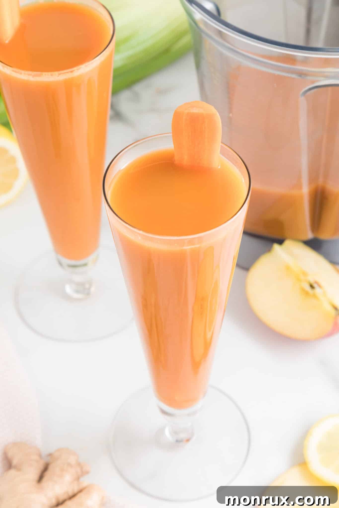 Caarot celery juice in a tall thin glass, garnished with a celery stalk.