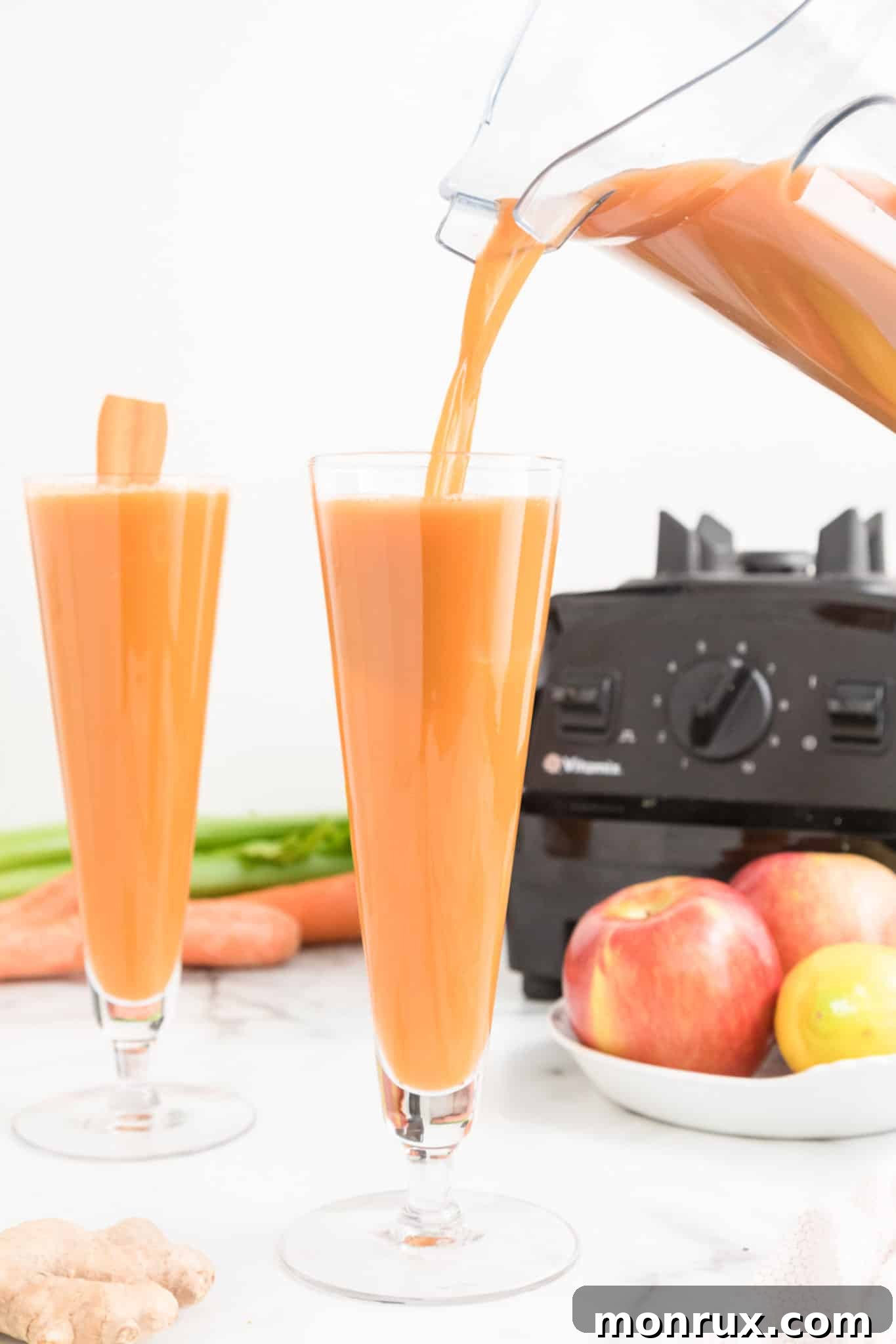 A blender pouring vibrant carrot celery juice into a tall glass, illustrating the final step of preparation.