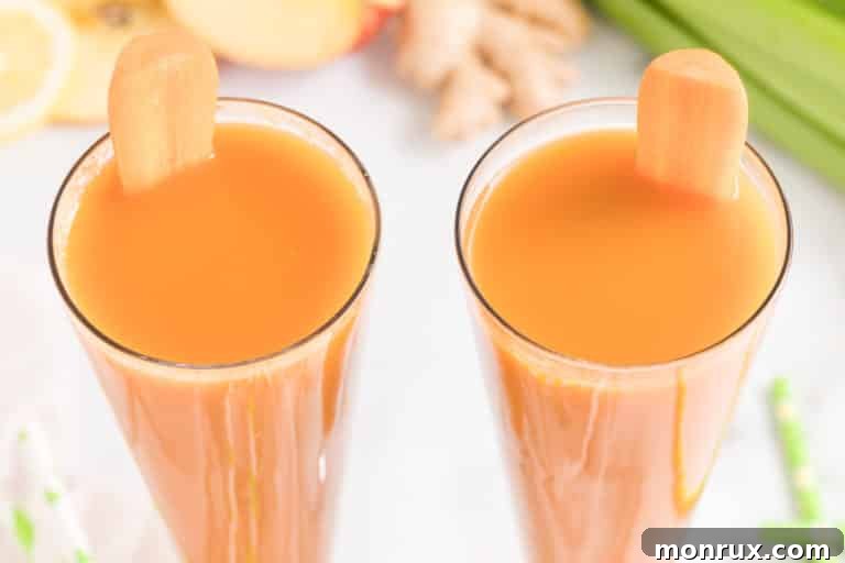 Two glasses of fresh made carrot celery juice, one garnished with a celery stalk.