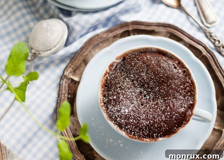 A close-up of a chocolate coconut flour mug cake on a rustic wooden table.
