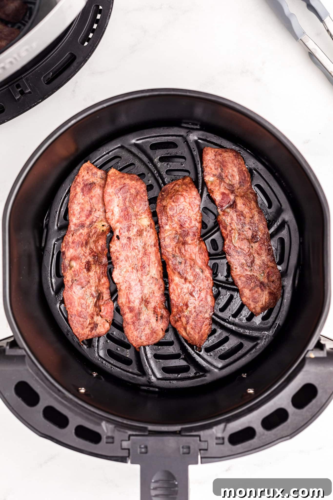 Crispy cooked turkey bacon slices ready to serve from an air fryer basket.