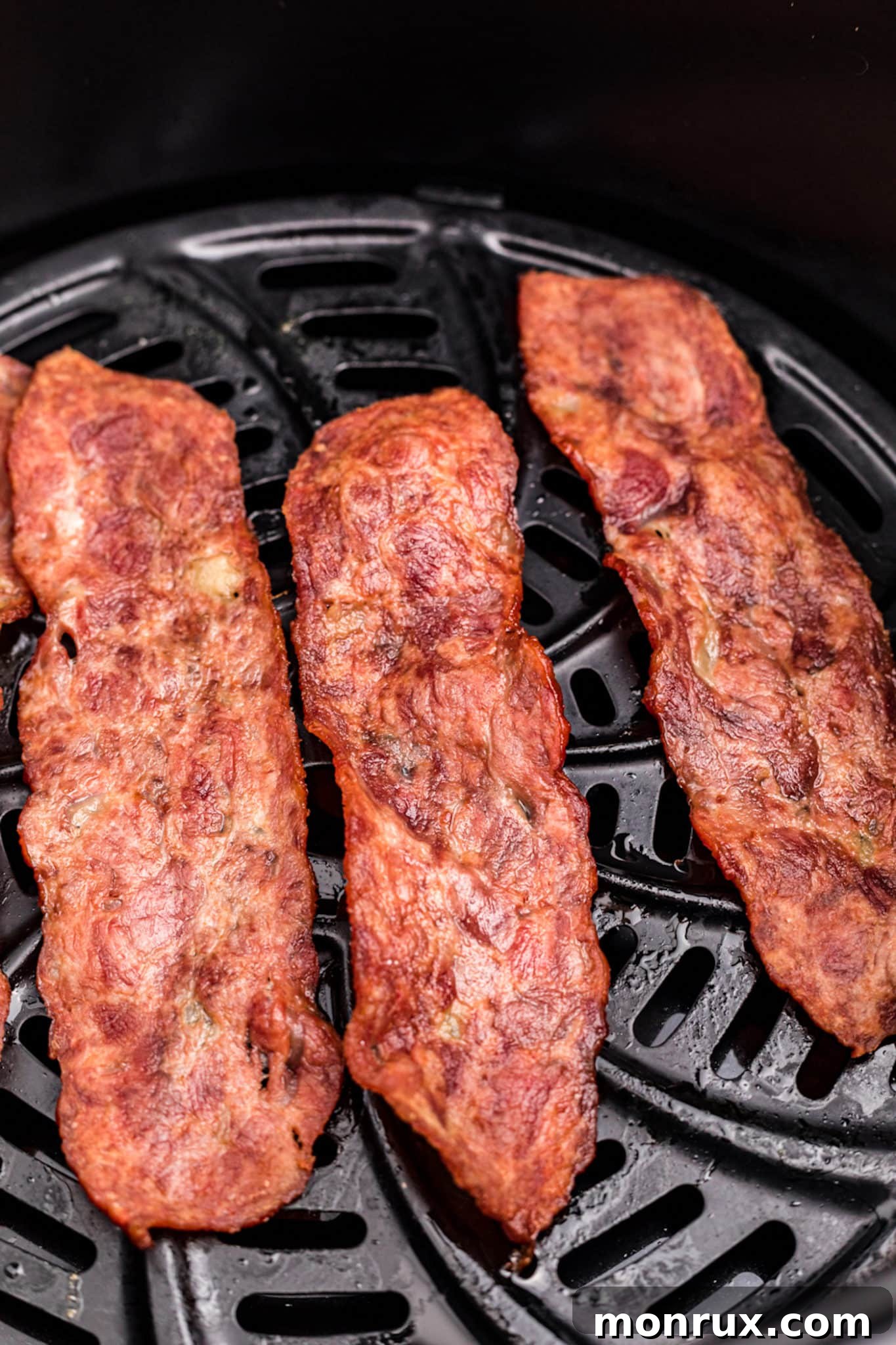 Crispy cooked turkey bacon slices after flipping, continuing to cook in the air fryer.