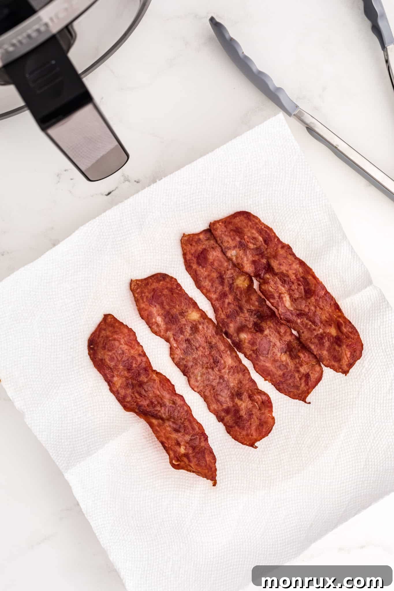 Cooked turkey bacon slices resting on paper towels to absorb excess grease.