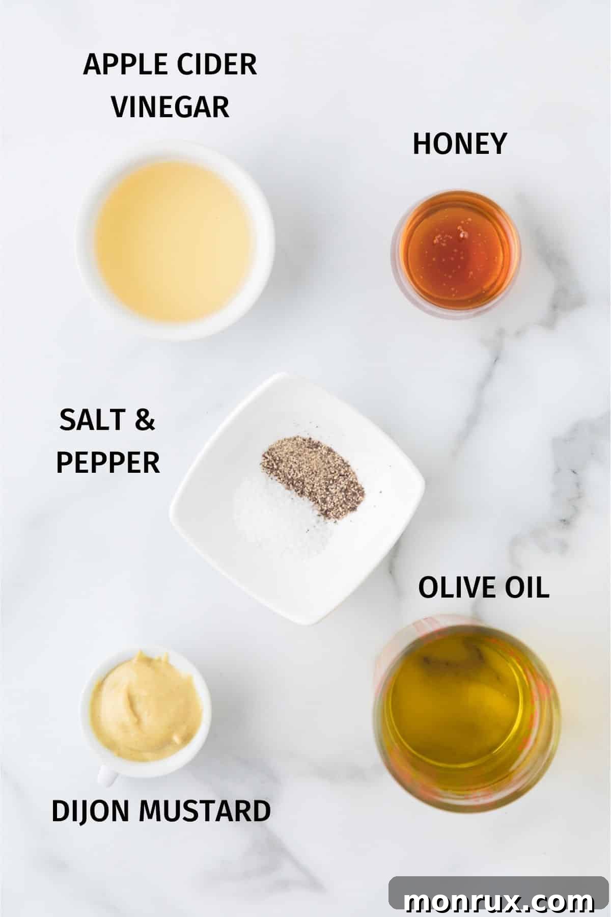 A rustic arrangement of key ingredients for honey mustard dressing including olive oil, Dijon mustard, honey, and fresh lemons, poised on a wooden surface.