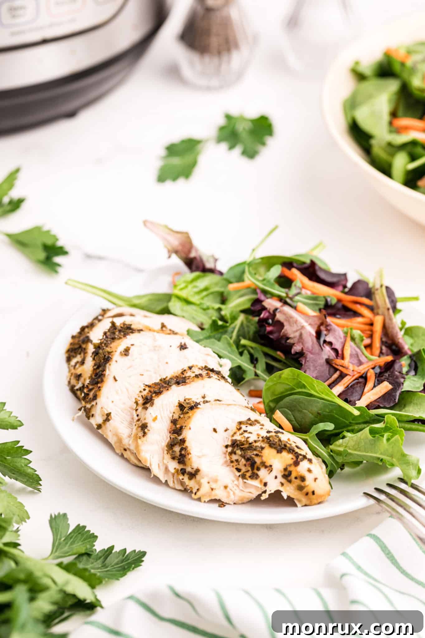 Perfectly sliced Instant Pot turkey tenderloin served on a plate alongside a fresh green salad, highlighting its tenderness and juicy texture.