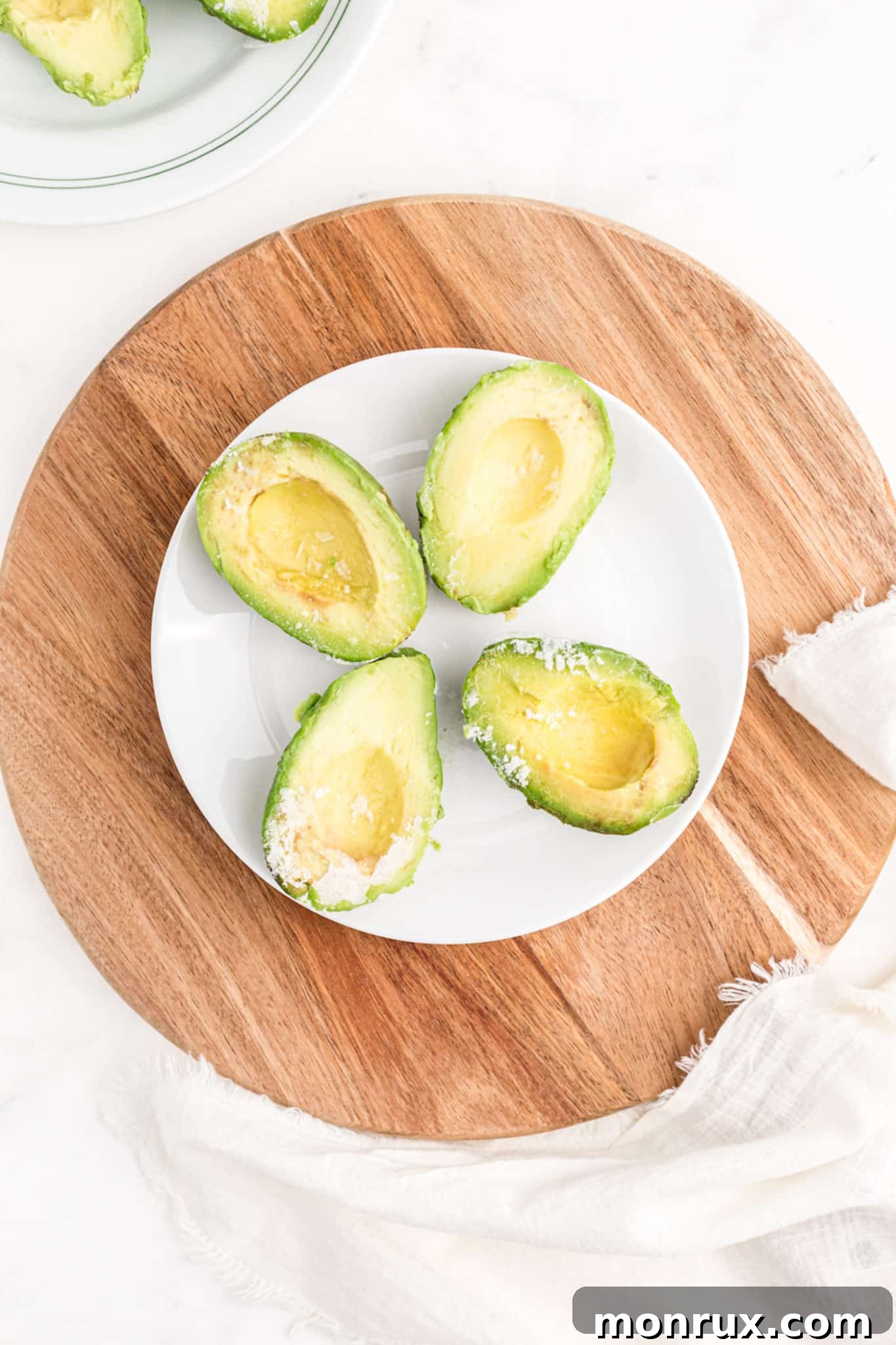 Plate with four frozen avocado halves, showing their preserved shape and color.