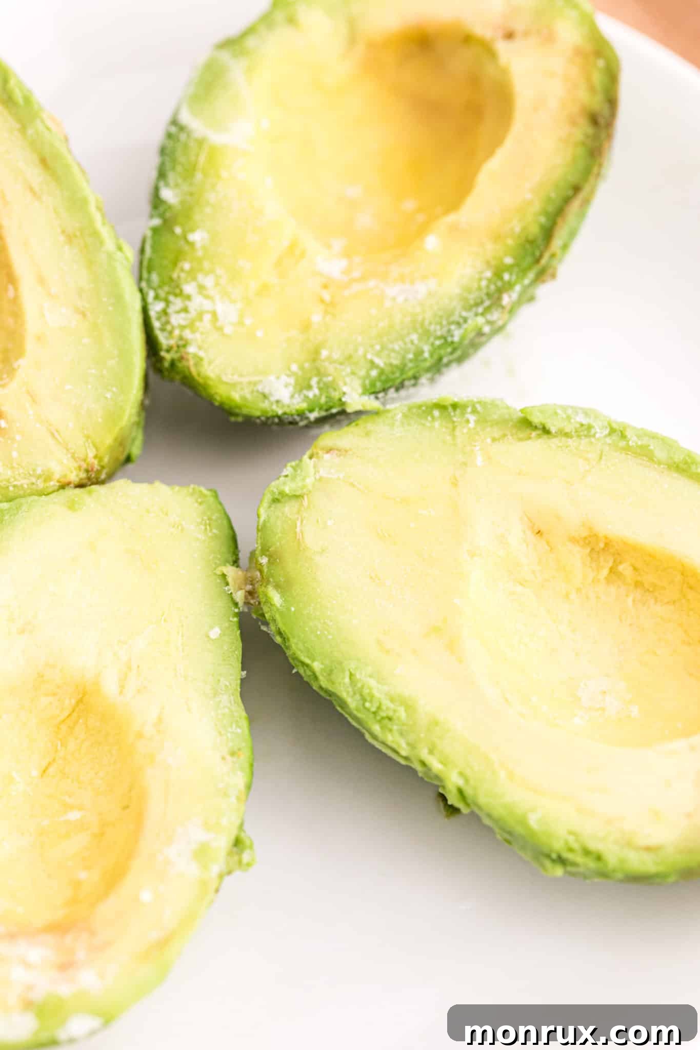 Plate with several frozen avocado halves, showing texture after freezing.