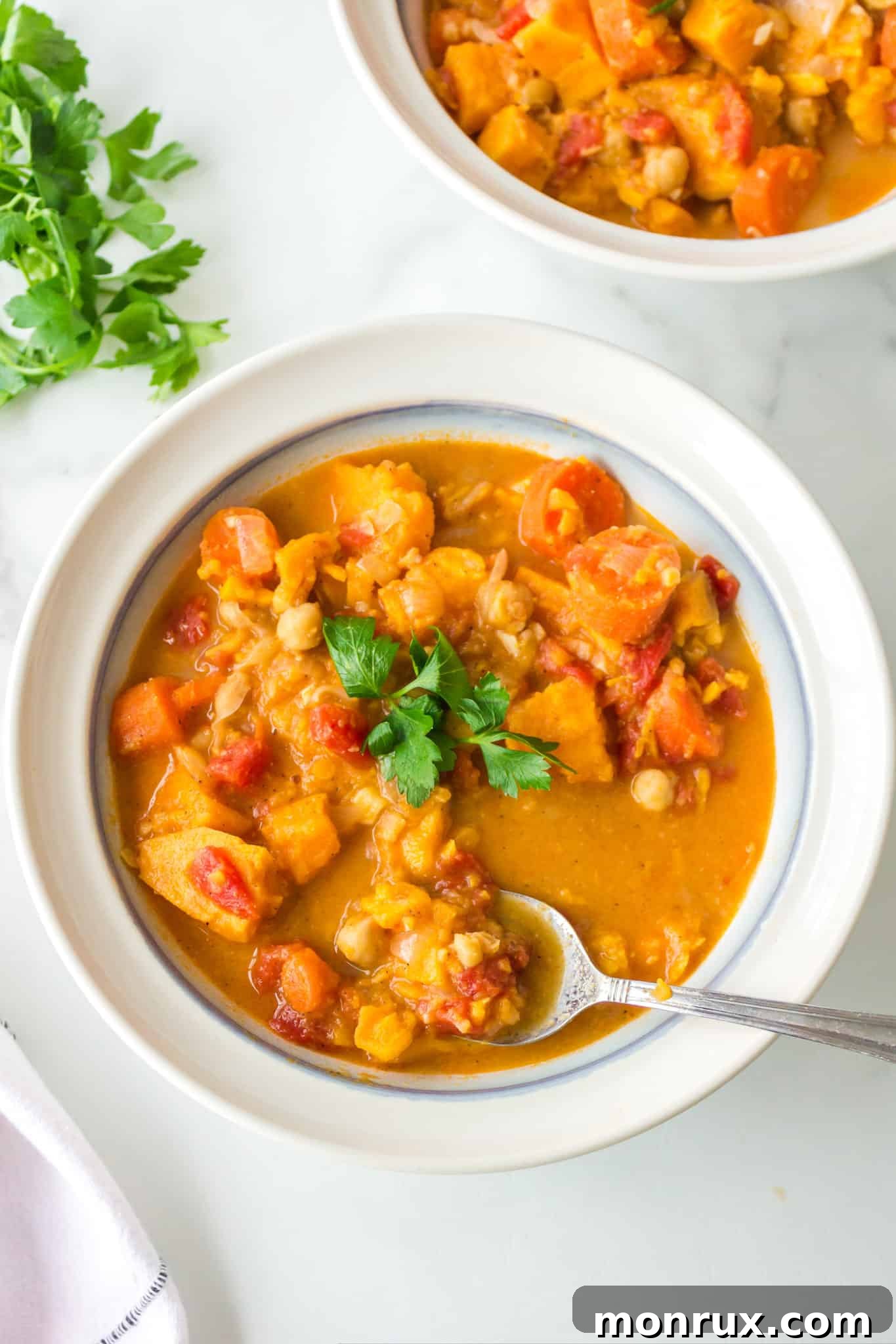 Two cozy bowls of vegan stew, rich with vegetables including tender cauliflower, are served on a wooden surface.