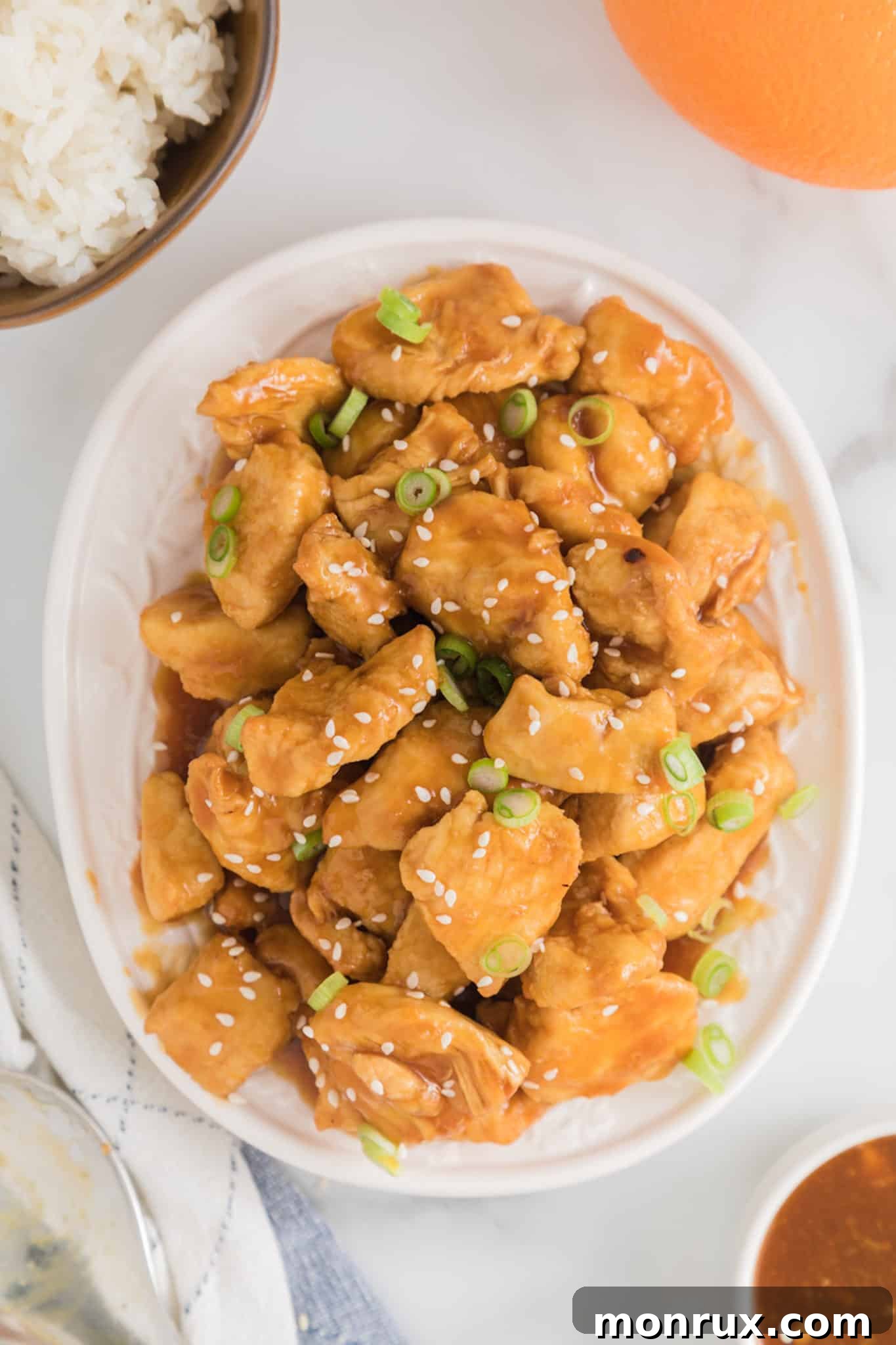 Completed air fryer orange chicken bites topped with sesame seeds and green onions.