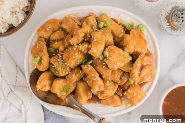 Completed air fryer orange chicken bites topped with sesame seeds and green onions.