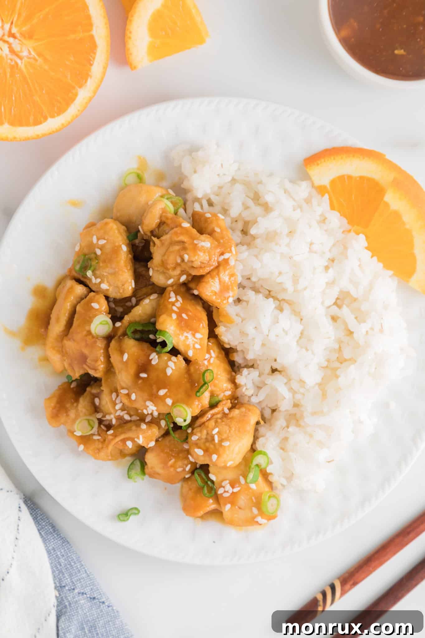 White rice and air fryer orange chicken on a white dinner plate.