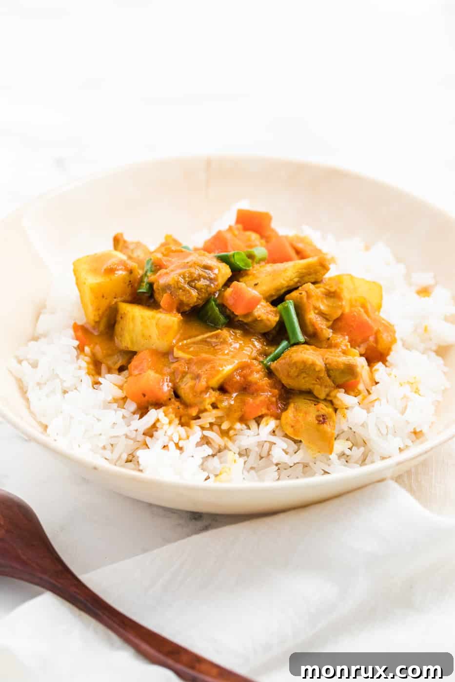 instant pot chicken curry with carrots and potatoes served in a bowl with steamed white rice.