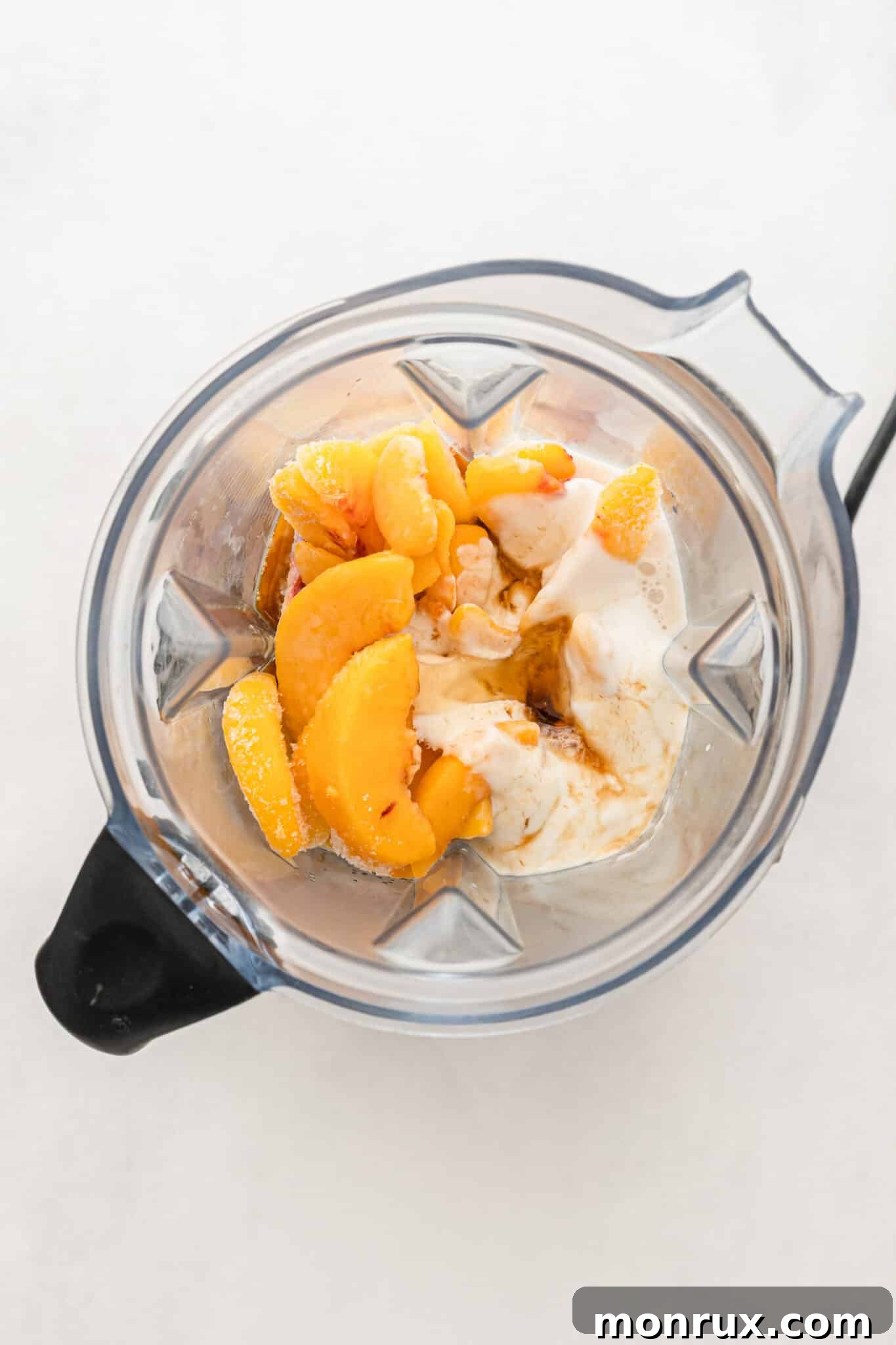 All ingredients for a peach banana smoothie placed in the jar of a blender, ready to be blended.