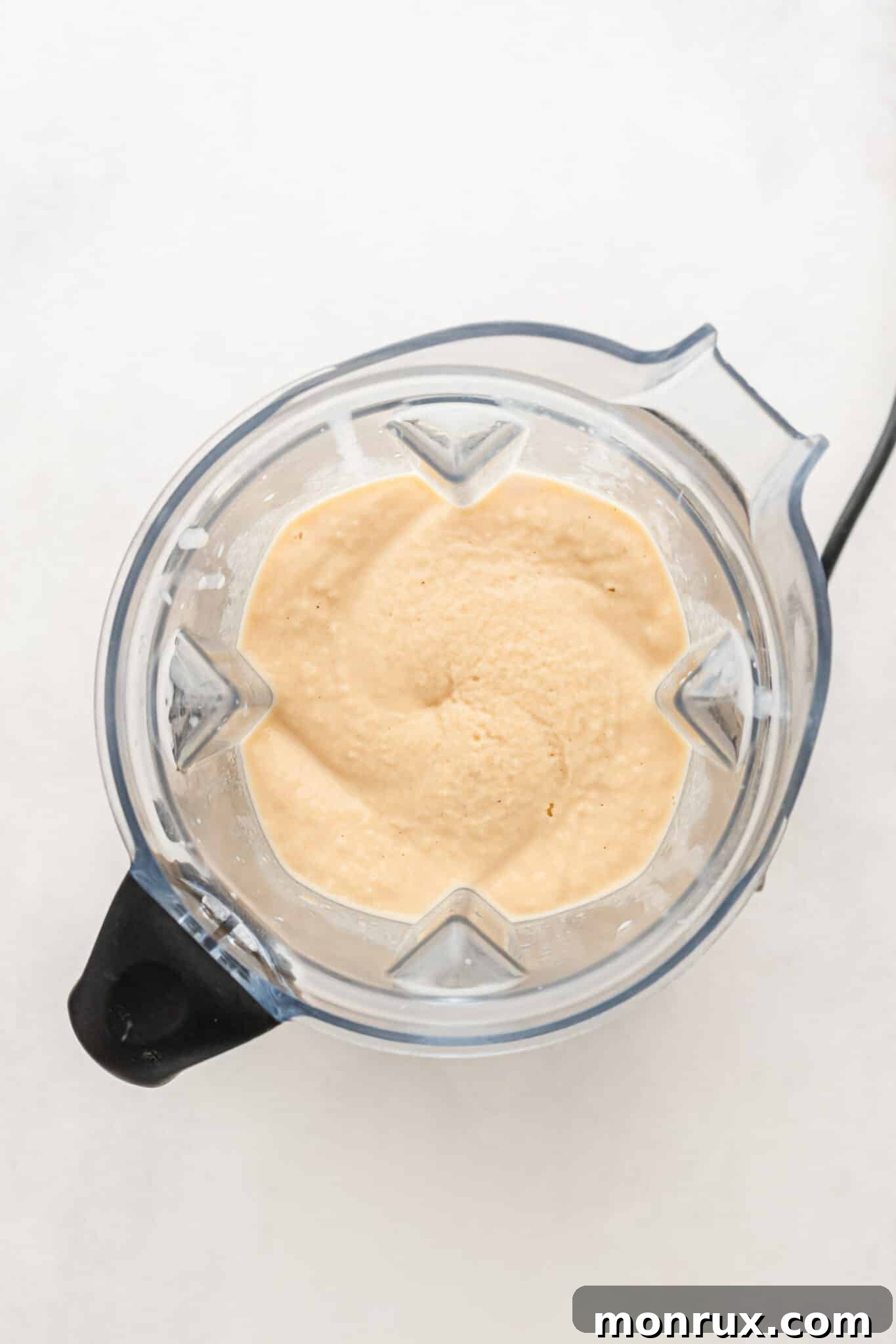 The blended banana peach smoothie swirling smoothly within the jar of a high-powered blender, indicating readiness to serve.