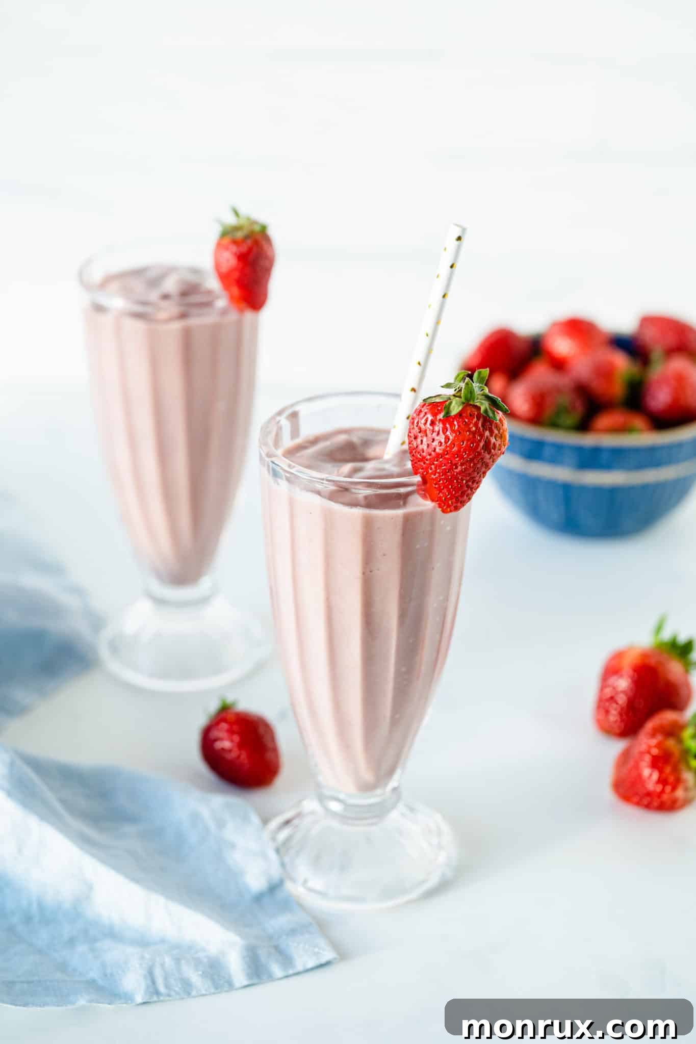 Two glasses of vibrant pink strawberry beet smoothie, garnished with fresh strawberries, ready to be enjoyed.