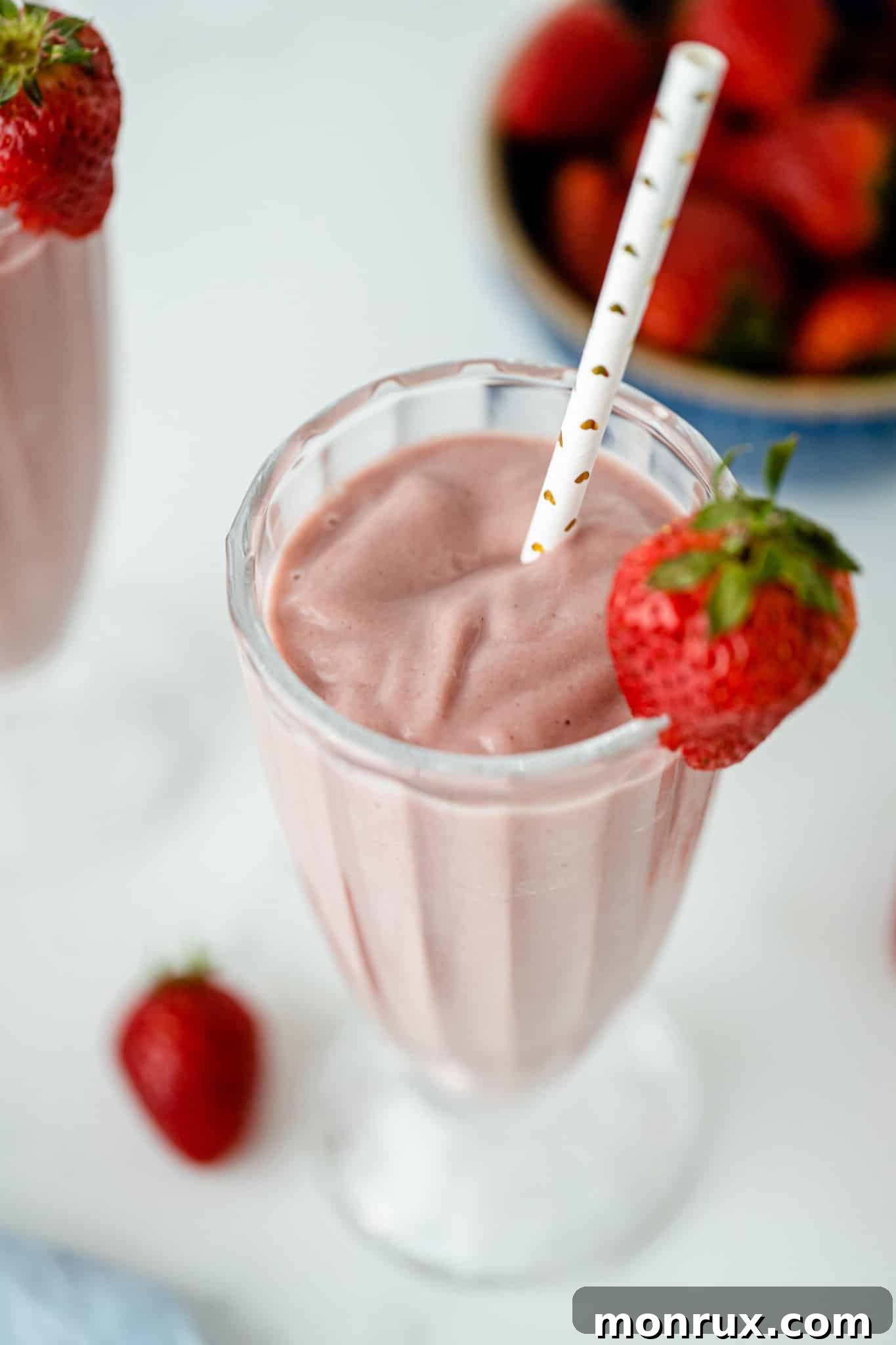 A single glass of creamy beet smoothie served with a straw and garnished with a small beet slice.