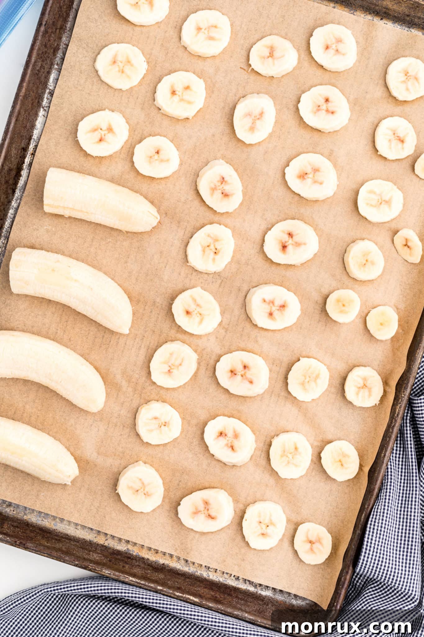 Banana halves and slices on a parchment-paper lined baking sheet.