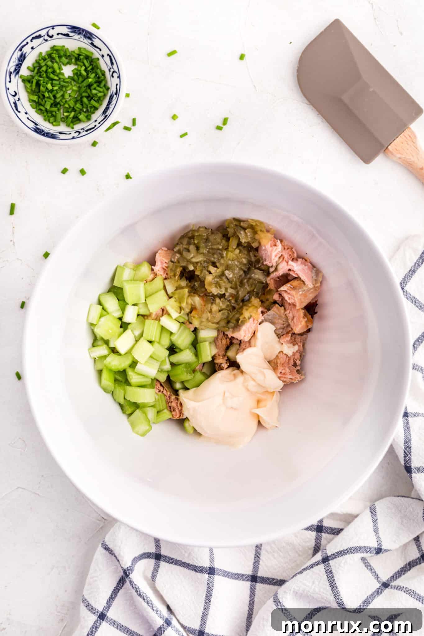 Diced salmon salad ingredients in a large white mixing bowl.