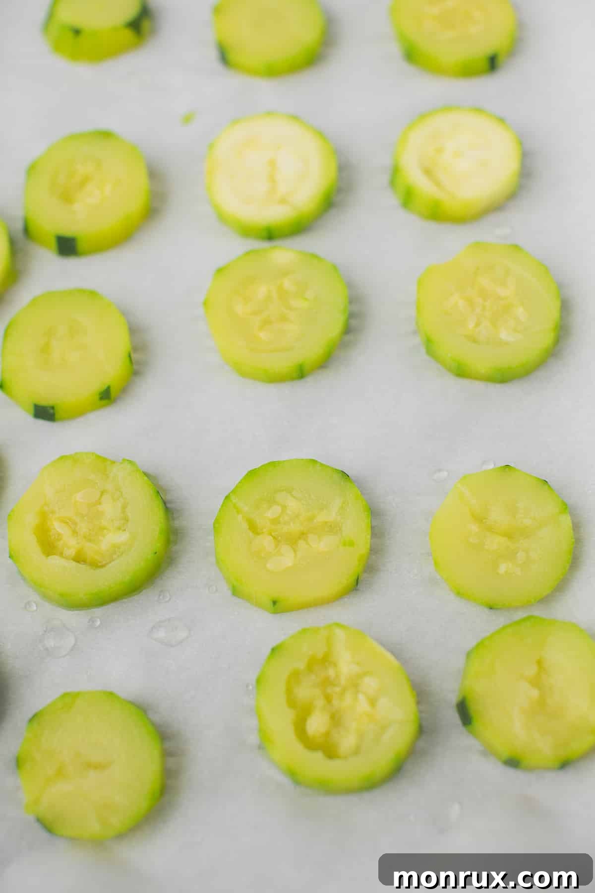 Steamed zucchini slices spread on a baking sheet, ready for freezing to be used in smoothies.