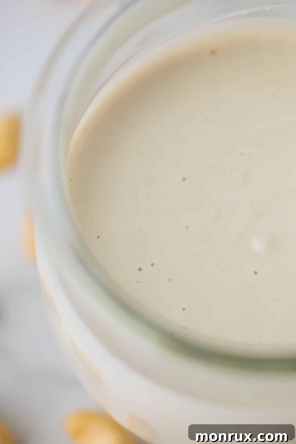 Smooth and creamy cashew sauce stored in a clear glass jar in the refrigerator.