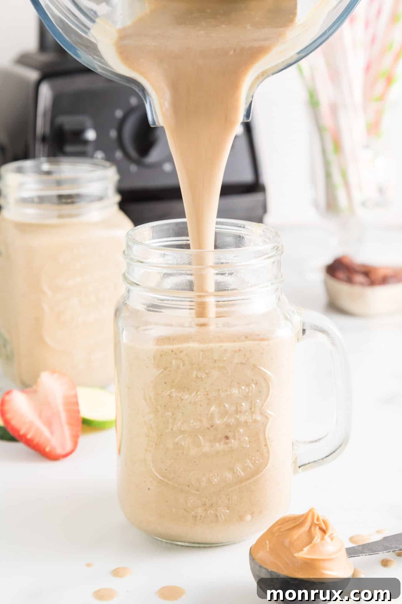 A rich strawberry zucchini smoothie being poured from a blender into an elegant mason jar, ready to be enjoyed.