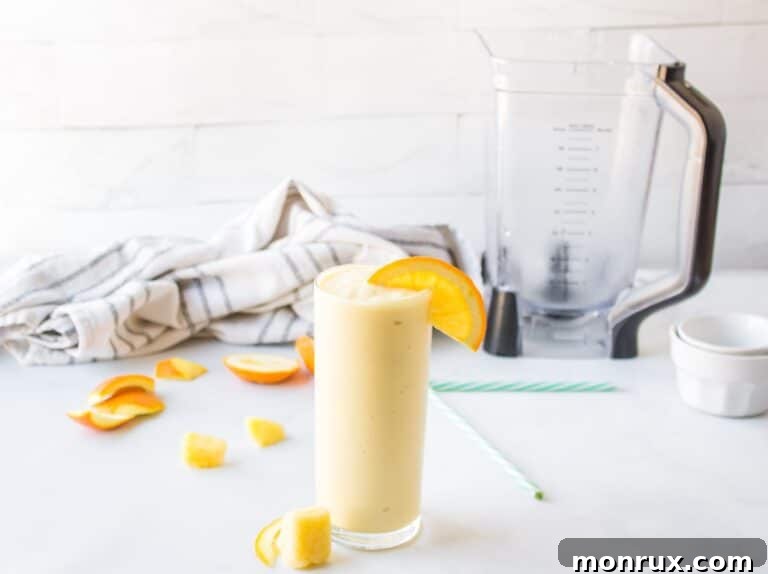 Close-up of a refreshing pineapple orange smoothie in a glass with a straw.