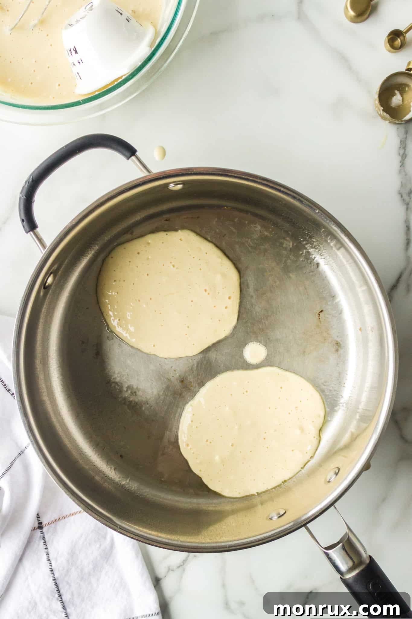 Pancake batter poured into a hot skillet, beginning to cook.