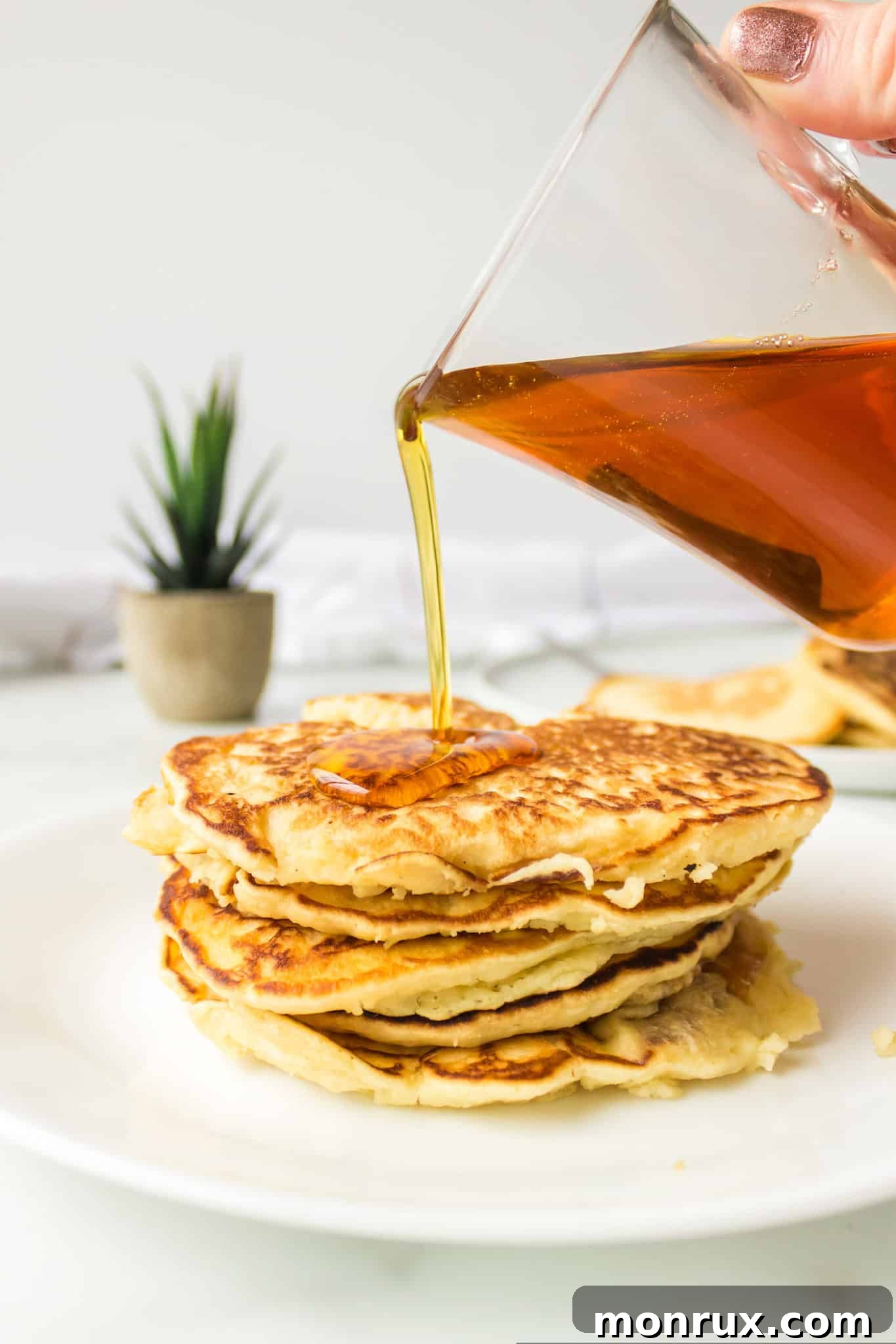 Maple syrup being poured generously over a stack of rice flour pancakes.