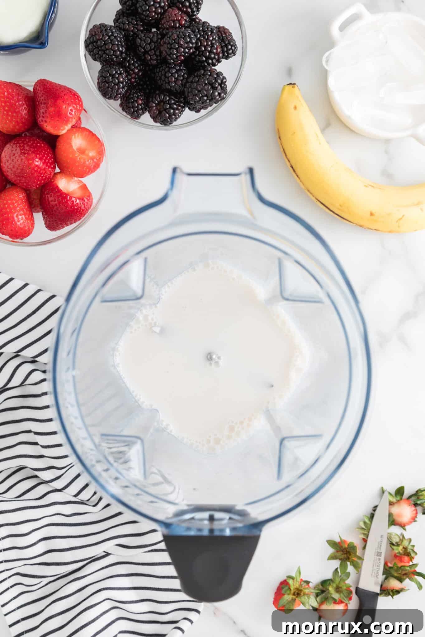 Almond milk being poured into the base of a high-powered blender.