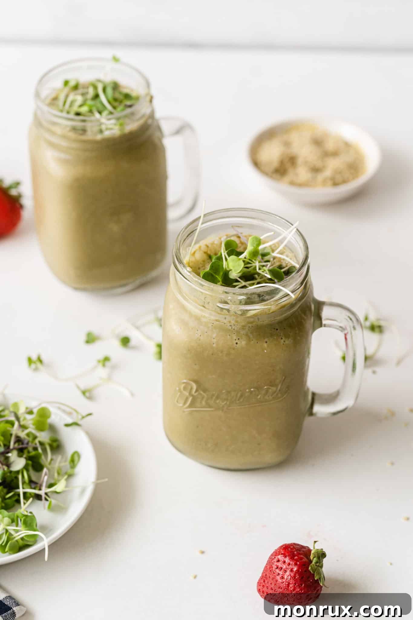 Two vibrant green broccoli sprout smoothies in glasses, garnished with fresh sprouts, on a rustic wooden table.