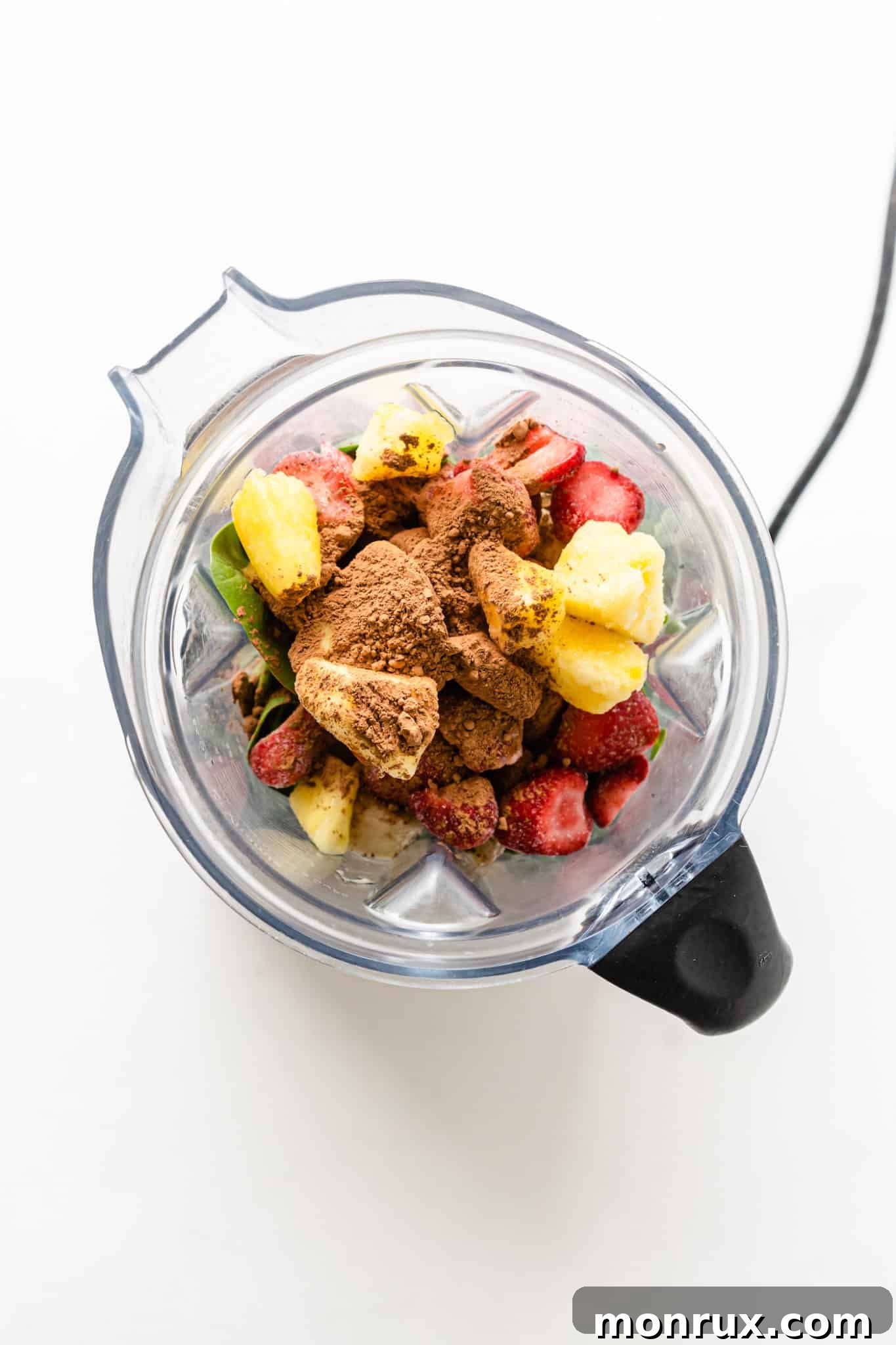 All the smoothie ingredients, including broccoli sprouts, spinach, frozen fruits, water, and hemp seeds, are loaded into a high-speed blender container, ready to be processed.