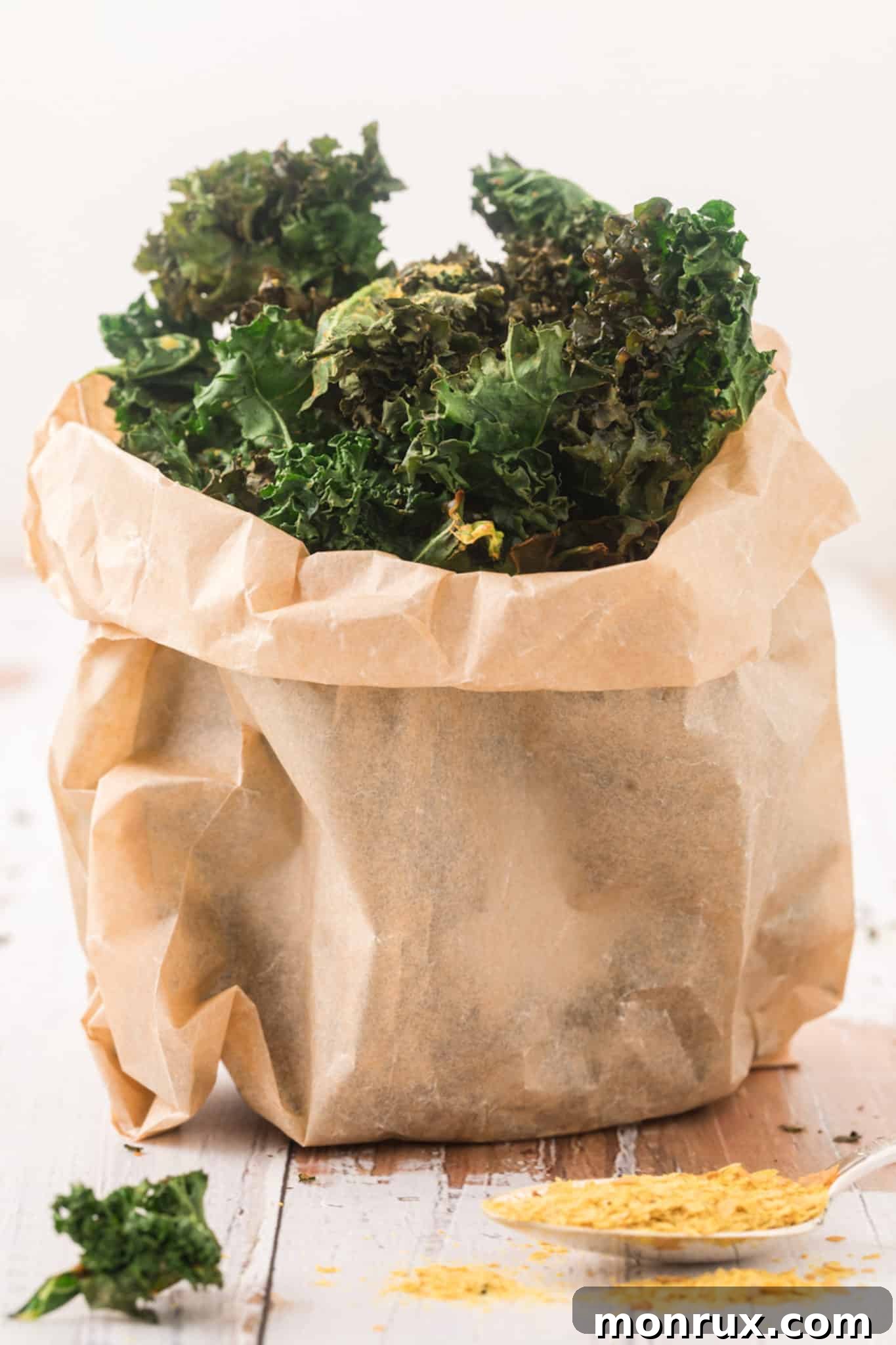 Crispy air fried kale chips served in a rustic paper bag on a wooden table, ready for a healthy snack.