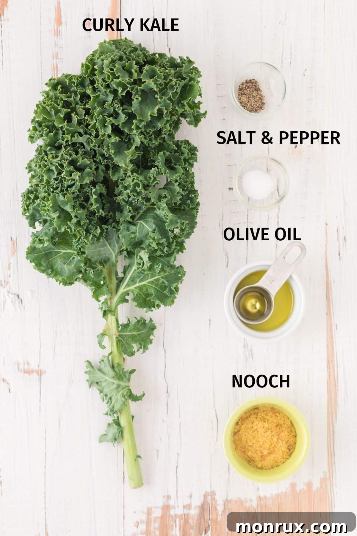 A vibrant selection of fresh ingredients for making air fryer kale chips, including a bunch of curly kale, olive oil, nutritional yeast, salt, and pepper.