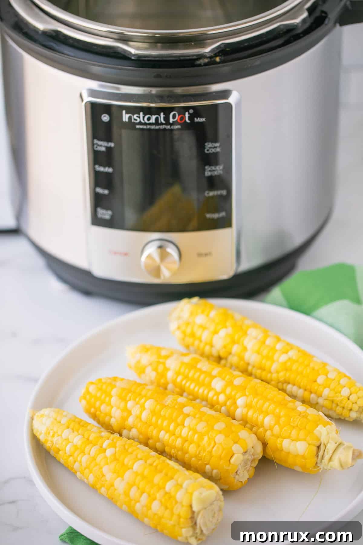 plate of cooked corn on the cob in front of an instant pot pressure cooker.