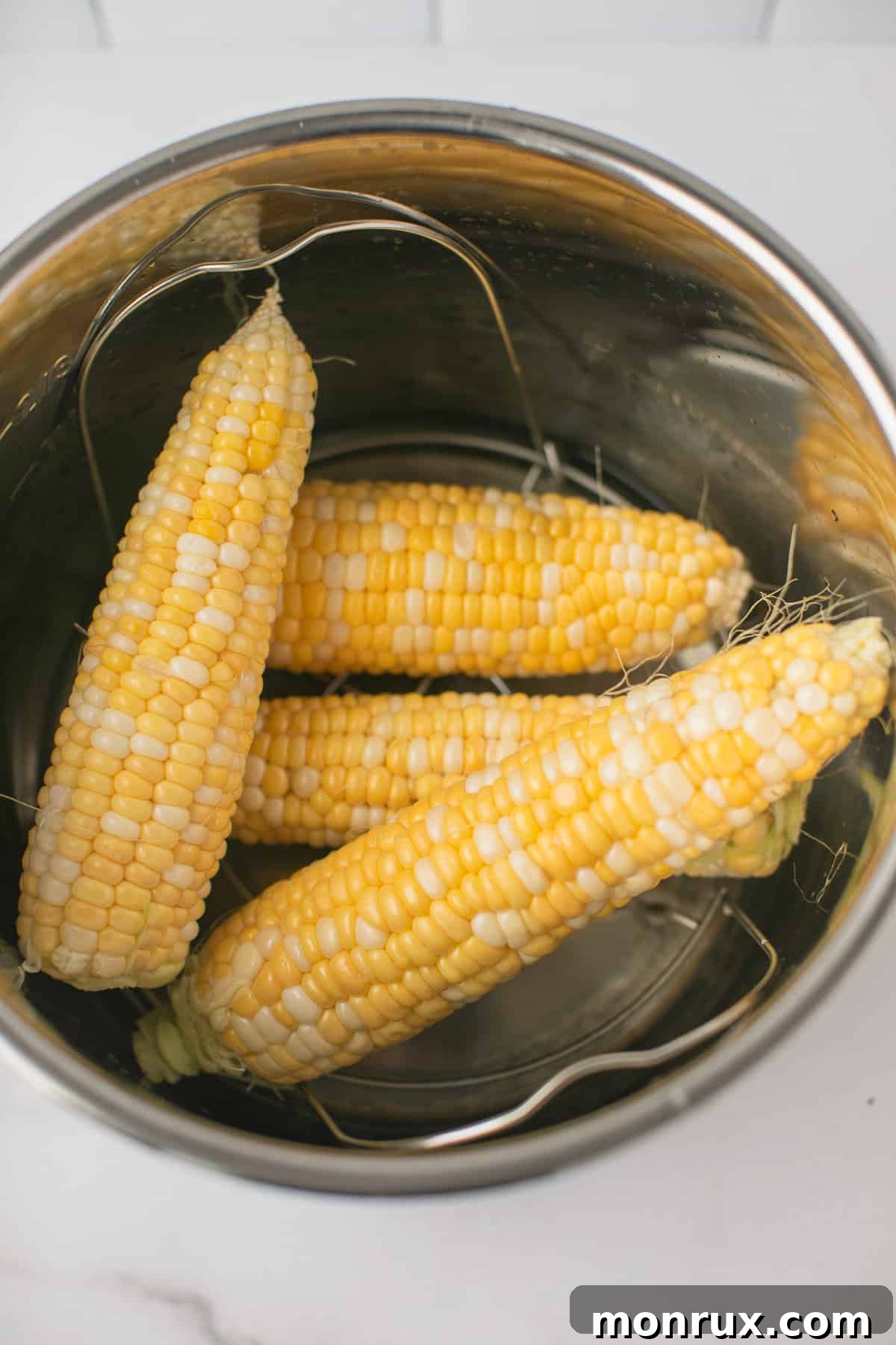 four pieces of corn on the cob inside an instant pot pressure cooker.