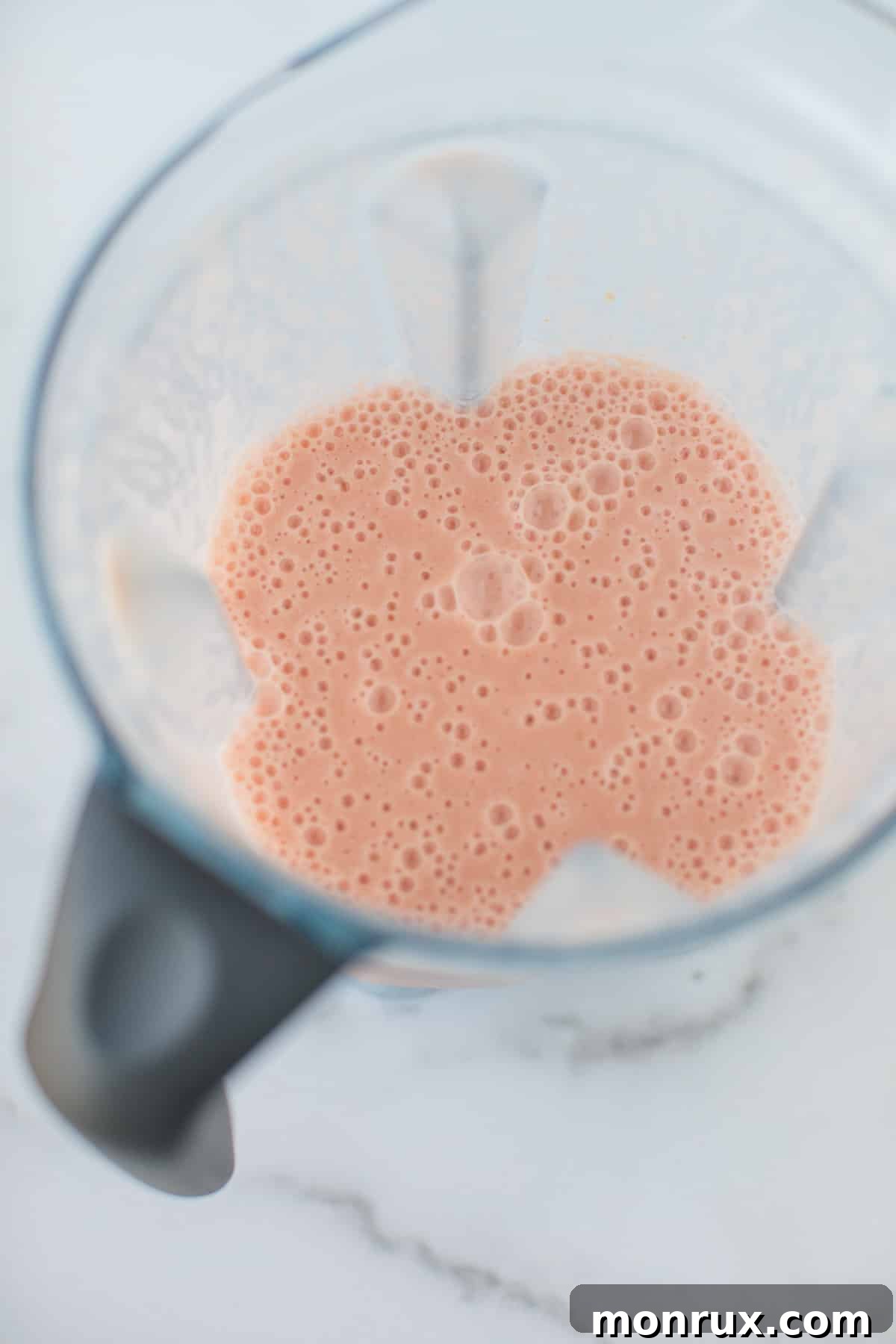 A perfectly blended, smooth grapefruit smoothie within the base of a high-speed blender, ready to be poured.