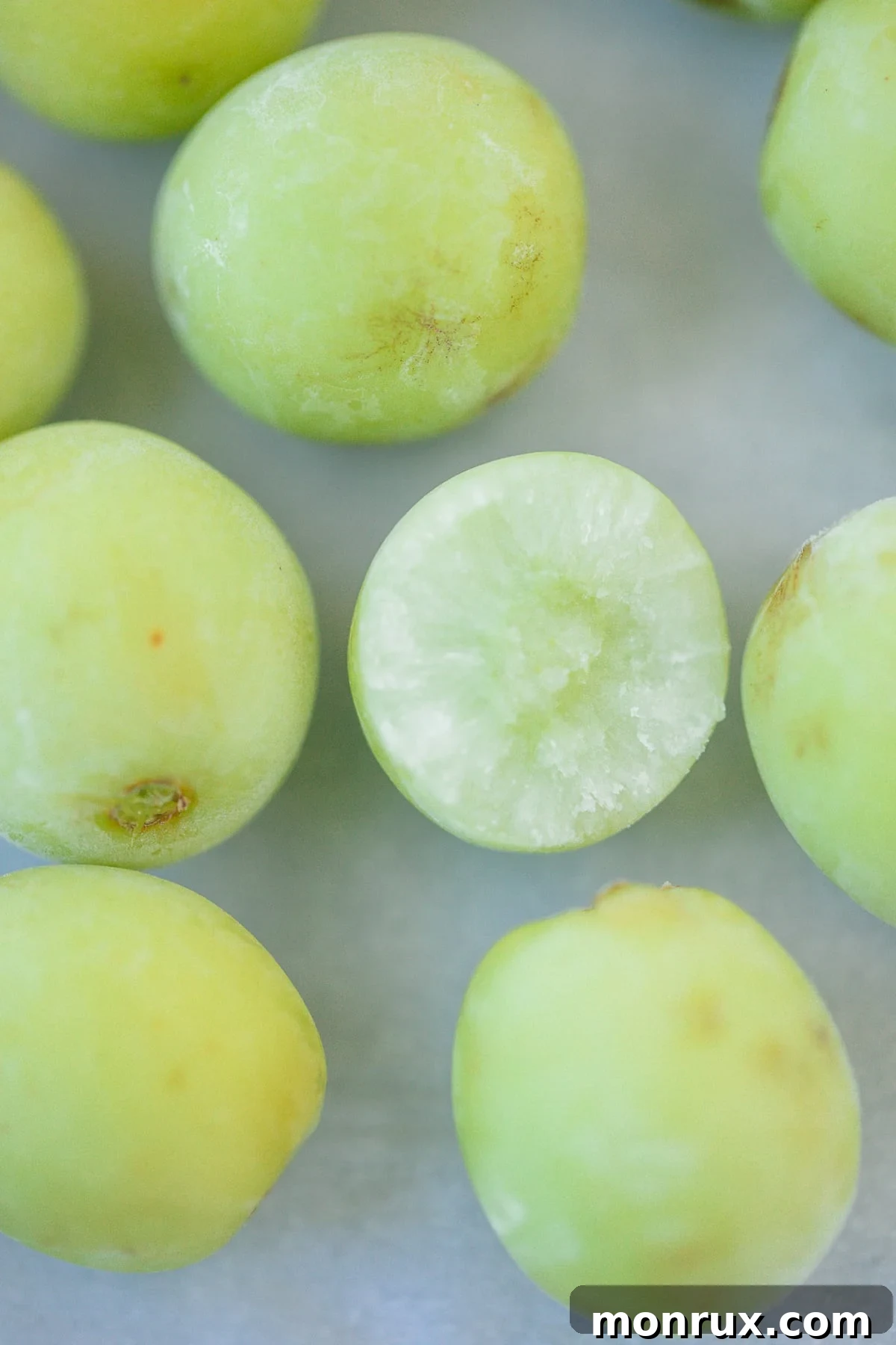 A clear glass bowl brimming with perfectly frozen green grapes, ready to be enjoyed as a refreshing snack.